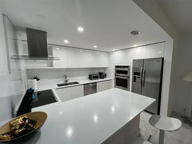 a kitchen with stainless steel appliances a sink a stove a refrigerator and cabinets