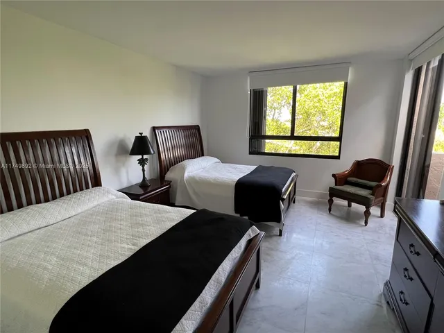 a bedroom with two beds and a dresser next to a window