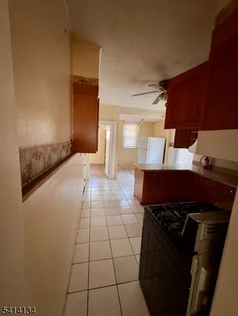 a view of a refrigerator in kitchen and an empty room in wooden floor