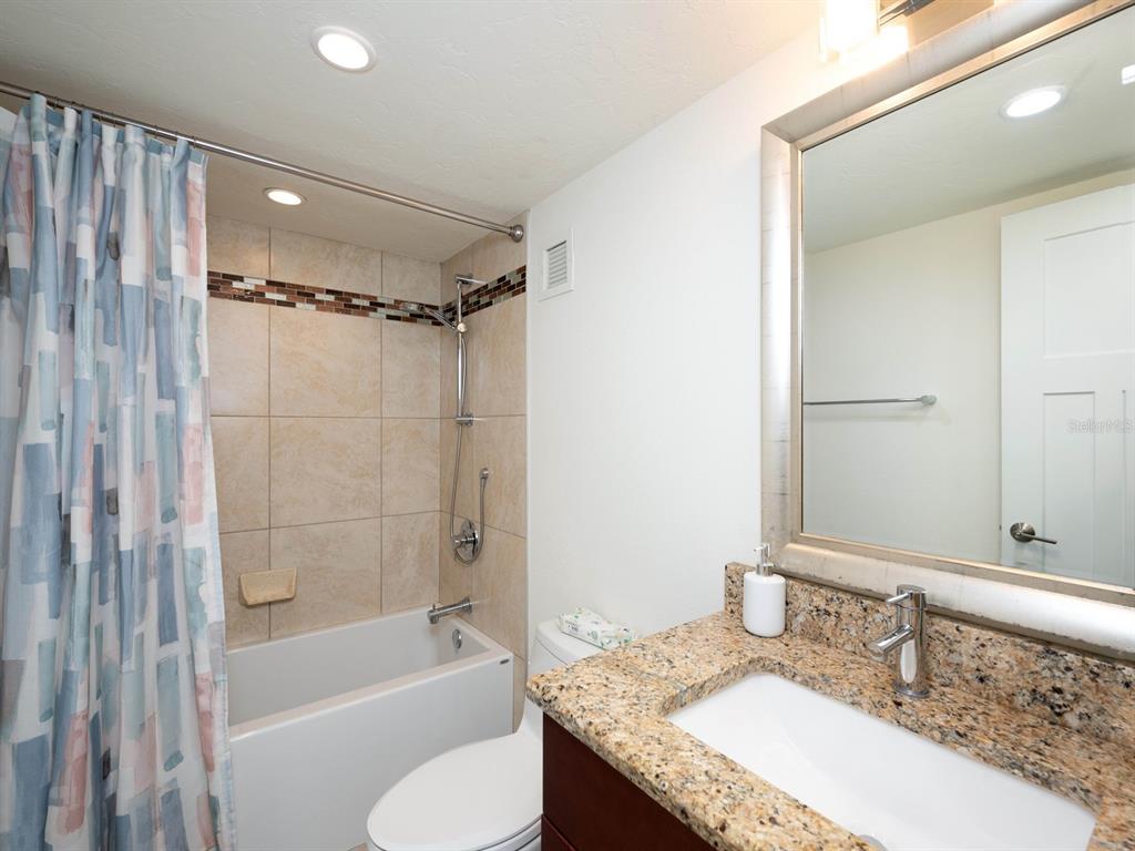 101 South Gulfstream Avenue, Unit 10E Sarasota, FL 34236 - Photo 11 of 54 a bathroom with a granite countertop bathtub shower sink vanity and toilet