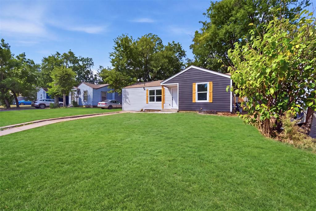 905 East Shaw Street Fort Worth, TX 76110 - Photo 6 of 19 Front exterior featuring gray horizontal siding, white trim, wood shutters, and a white entry door