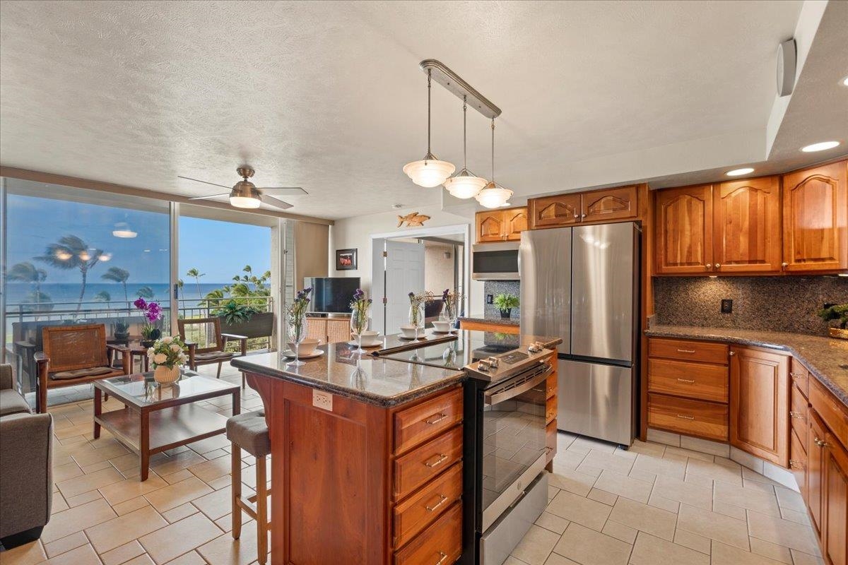 1993 South Kihei Road, Unit 601 Kihei, HI 96753 - Photo 14 of 45 a kitchen with stainless steel appliances granite countertop a stove refrigerator a dining table and chairs with wooden floor