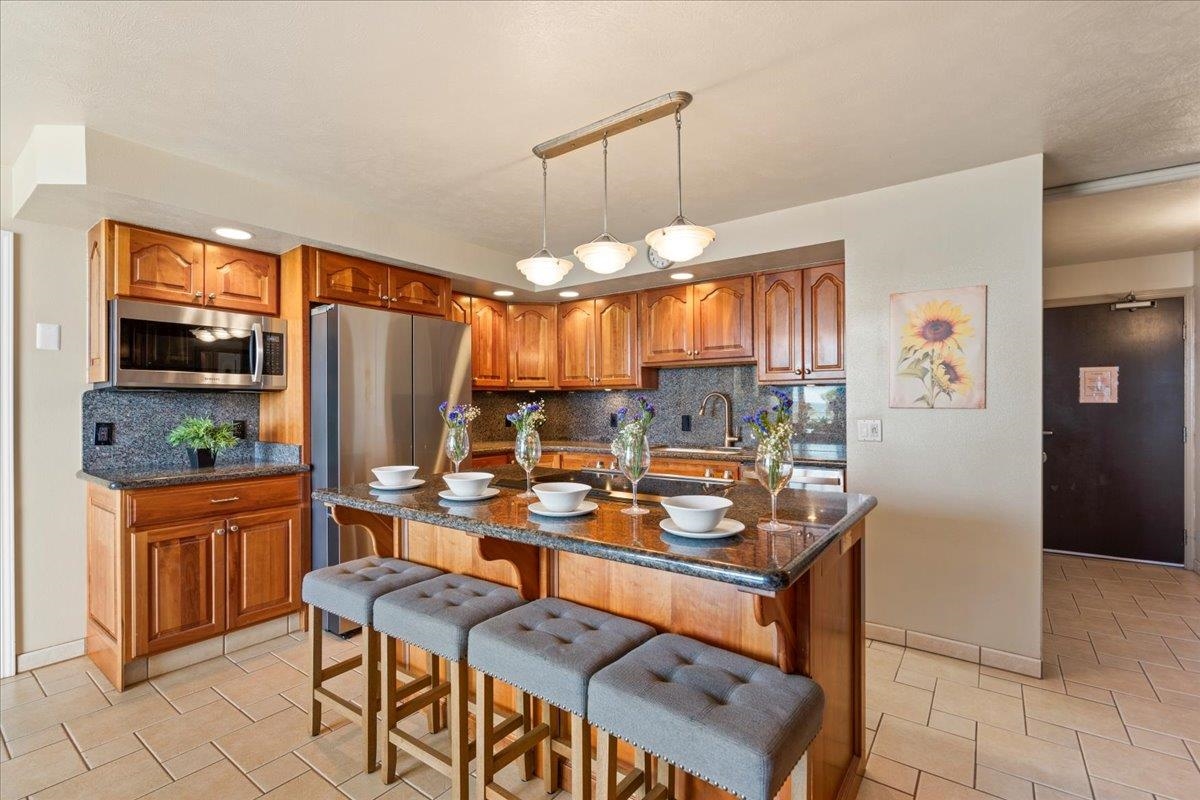 1993 South Kihei Road, Unit 601 Kihei, HI 96753 - Photo 10 of 45 a room with stainless steel appliances kitchen island granite countertop a refrigerator a stove a sink a dining table and chairs with wooden floor