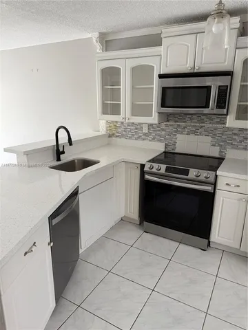 a kitchen with granite countertop a stove top oven microwave and a sink