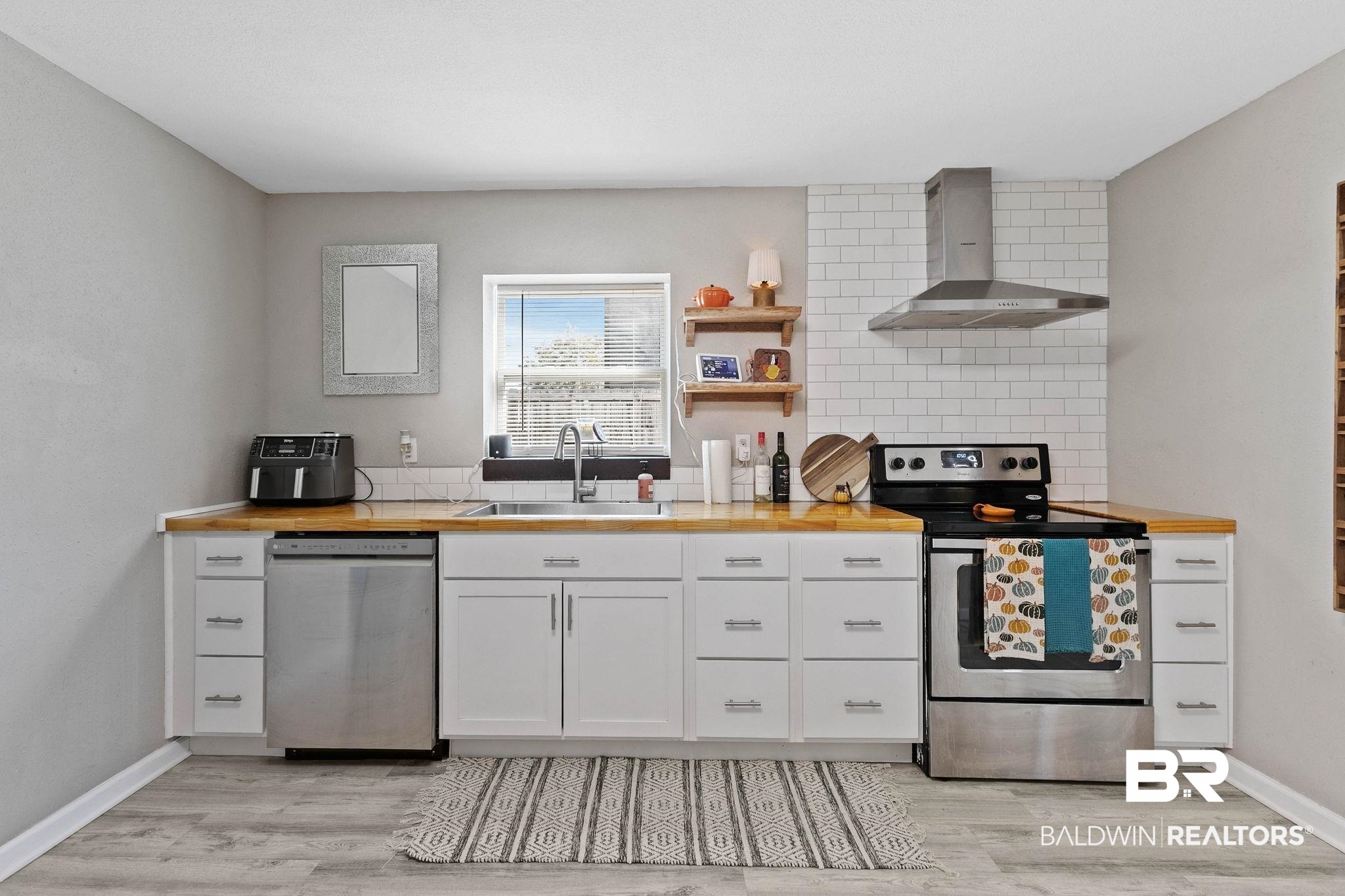 16796 Thompson Road Loxley, AL 36551 - Photo 28 of 93 Kitchen featuring decorative backsplash, appliances with stainless steel finishes, wall chimney exhaust hood, and white cabinetry
