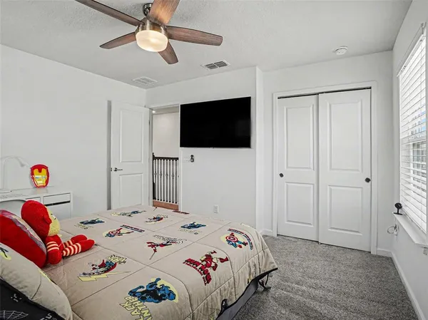 a bedroom with a bed a flat screen tv and a window