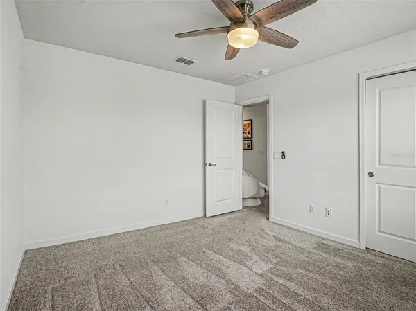 an empty room with closet and a ceiling fan