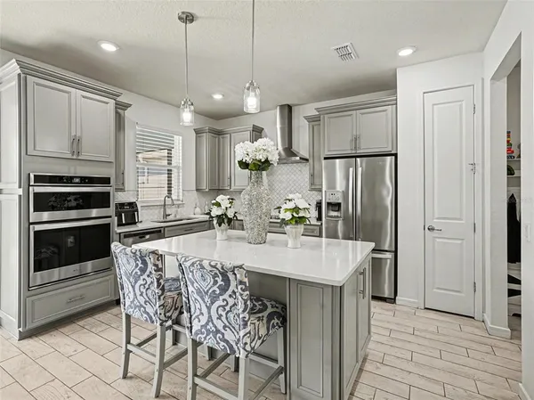 a large kitchen with granite countertop a table chairs stainless steel appliances and cabinets