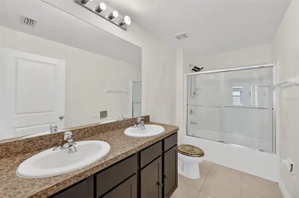 a bathroom with a granite countertop sink a toilet a mirror and shower