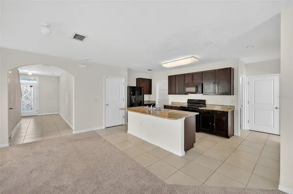 a large white kitchen with a stove a sink a microwave and a refrigerator