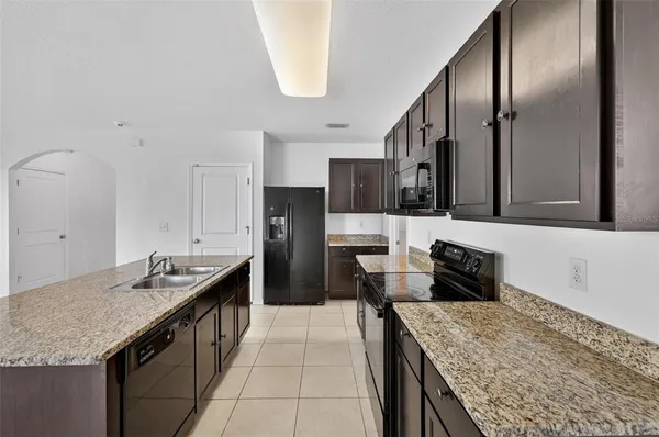 a kitchen with granite countertop kitchen island stainless steel appliances a sink stove and refrigerator