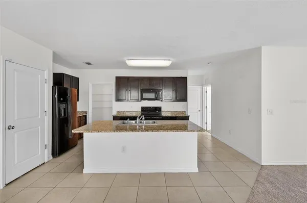 a view of a kitchen with kitchen island stainless steel appliances a sink a counter top space and cabinets
