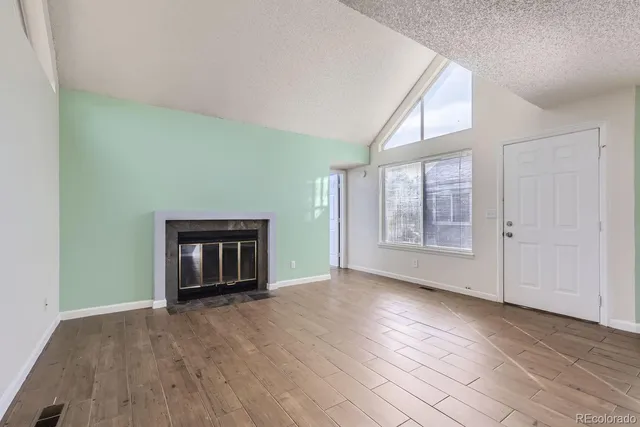 an empty room with wooden floor cabinet and windows