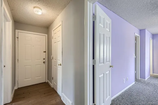 a view of a hallway with wooden floor and closet area