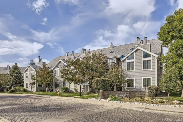 a view of a white building among the street and trees