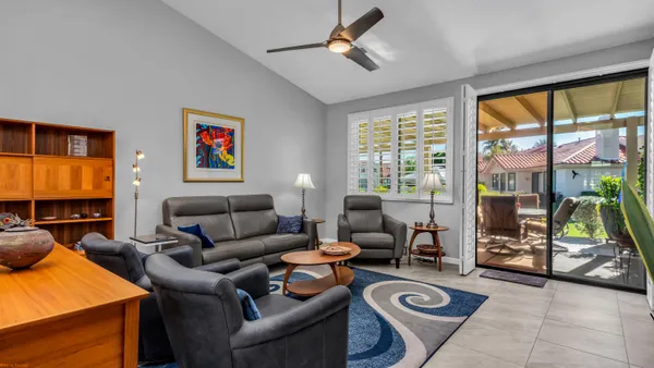 a living room with furniture a flat screen tv and a floor to ceiling window