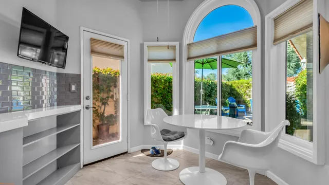 a living room with furniture a flat screen tv and floor to ceiling windows