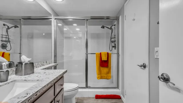 a bathroom with a granite countertop sink a mirror and shower