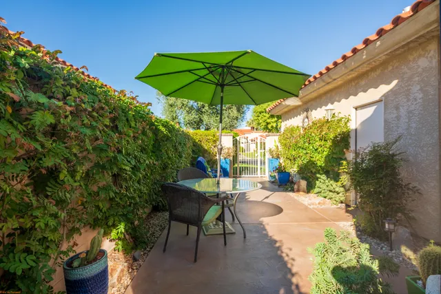 a backyard of a house with table and chairs under an umbrella