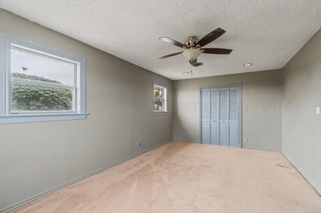 a view of a big room with windows and chandelier fan