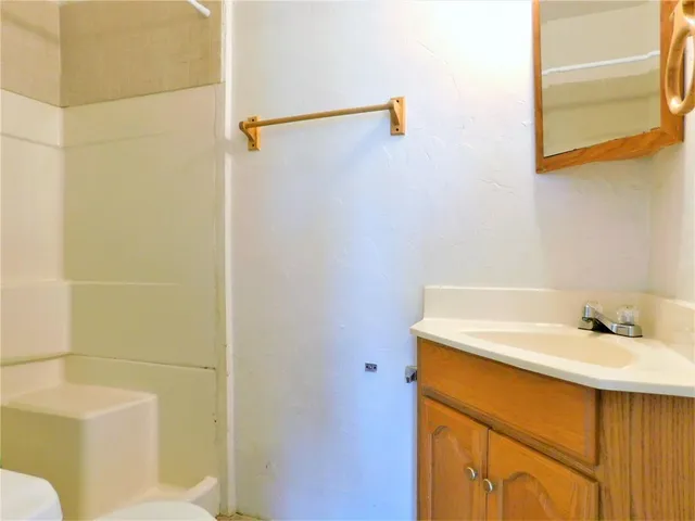 an empty room with wooden floor cabinet and windows