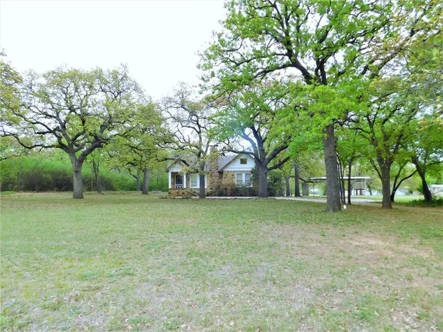 a brick house with a big yard and large trees