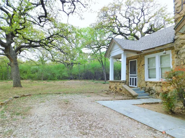 a view of a yard in front of a house with large tree
