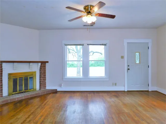 an empty room with a fireplace and wooden floor