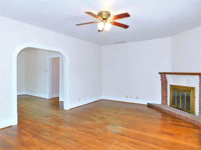 an empty room with chandelier fan and fireplace