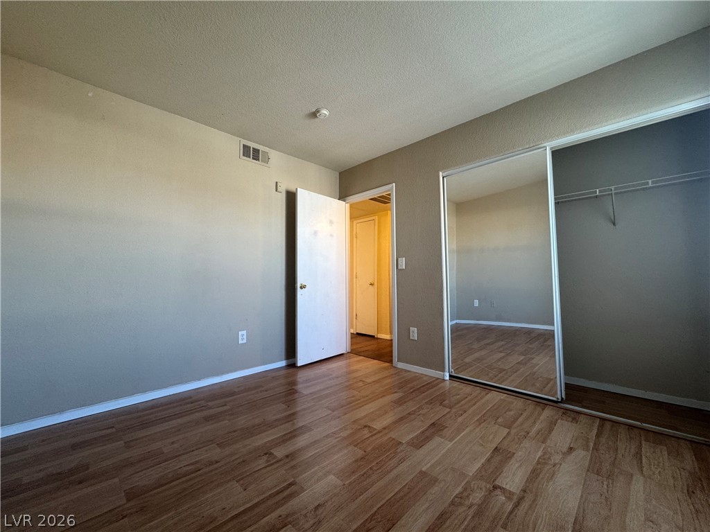 7255 West Sunset Road, Unit 2081 Las Vegas, NV 89113 - Photo 19 of 20 Unfurnished bedroom featuring dark wood finished floors, a closet, and a textured ceiling