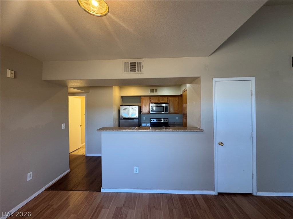 7255 West Sunset Road, Unit 2081 Las Vegas, NV 89113 - Photo 5 of 20 Kitchen with wood finish cabinets, a peninsula, stainless steel appliances, and dark wood-style floors