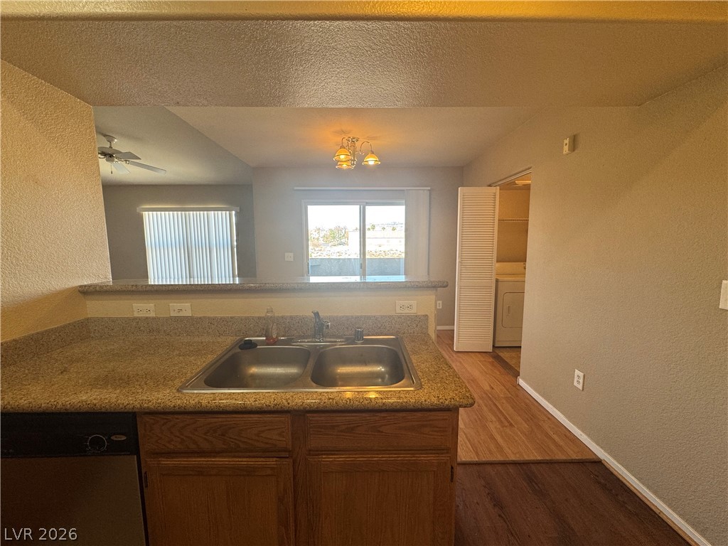 7255 West Sunset Road, Unit 2081 Las Vegas, NV 89113 - Photo 6 of 20 Kitchen featuring a textured wall, dishwasher, wood finished floors, washer / clothes dryer, and a peninsula