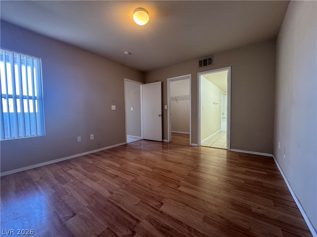 7255 West Sunset Road, Unit 2081 Las Vegas, NV 89113 - Photo 7 of 20 Unfurnished bedroom featuring a walk in closet, wood finished floors, and connected bathroom