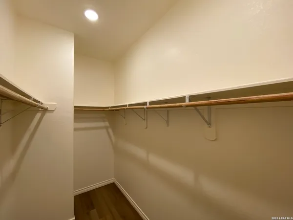 a view of an empty room with wooden floor and a ceiling fan