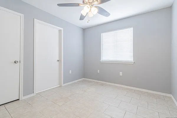 an empty room with chandelier fan and windows