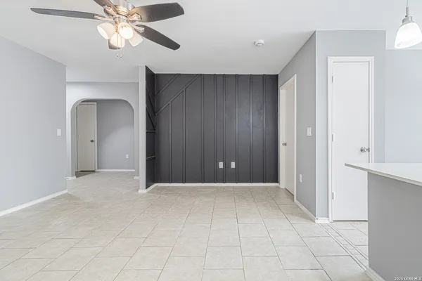 a view of an empty room with chandelier fan