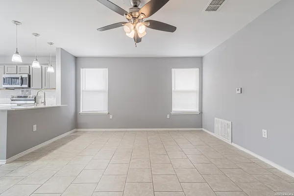 a view of an empty room with window and chandelier fan