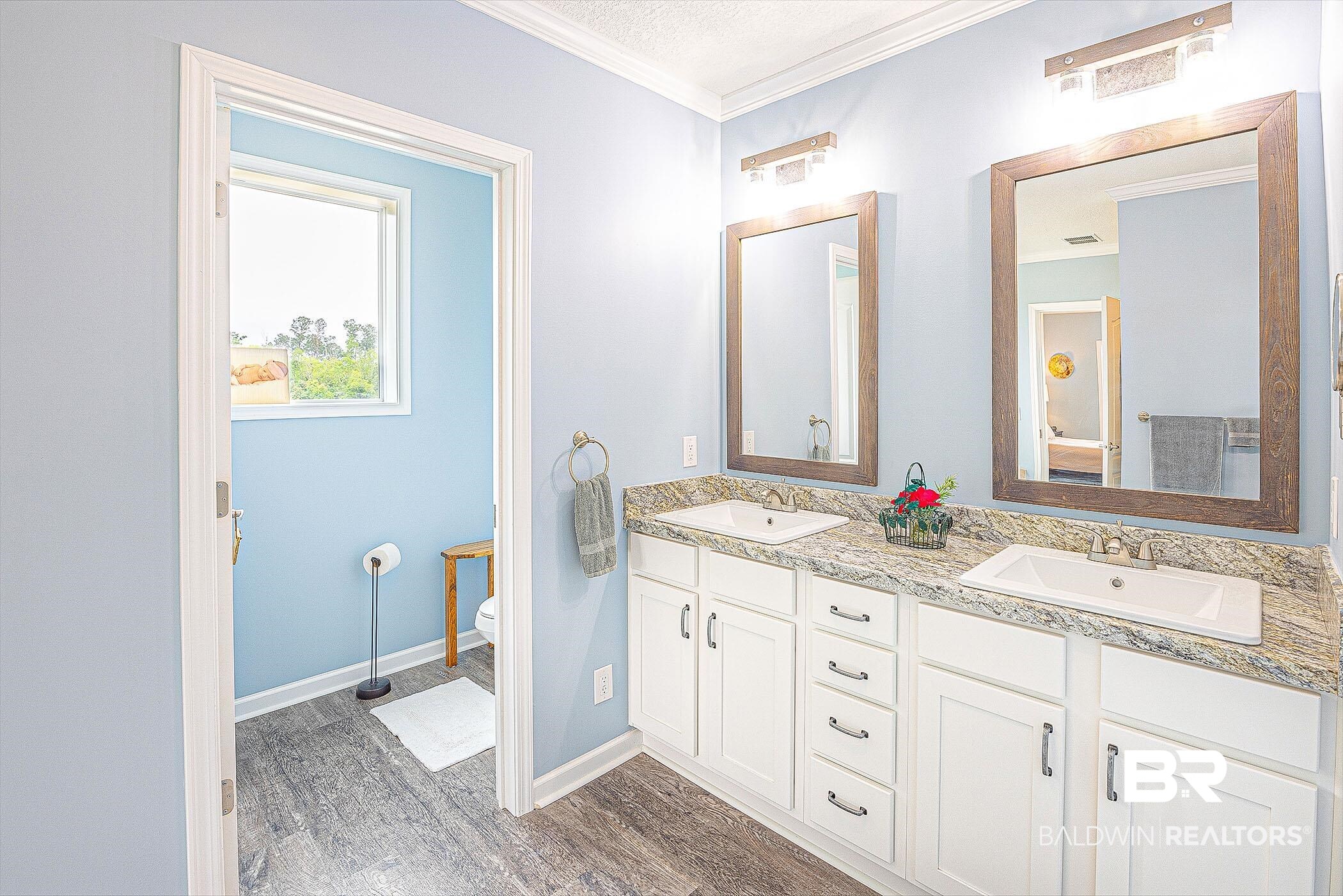 16000 John Bauer Road Summerdale, AL 36580 - Photo 21 of 34 Full bathroom with double vanity, ornamental molding, a sink, and wood finished floors