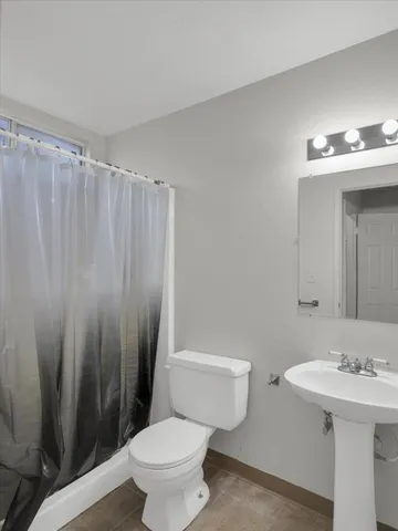 a bathroom with a sink a toilet a mirror and shower curtain