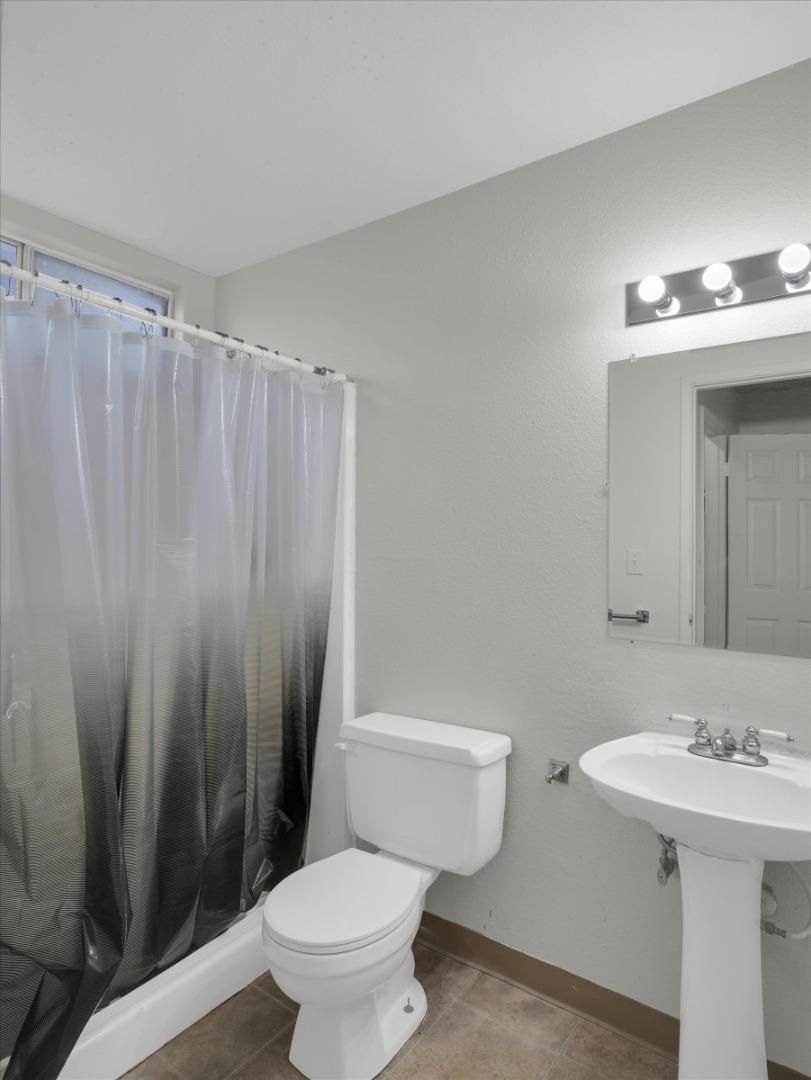 3559 Vernal Avenue Merced, CA 95340 - Photo 19 of 25 a bathroom with a sink a toilet a mirror and shower curtain