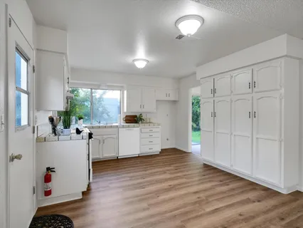 a kitchen with white cabinets and wooden floor
