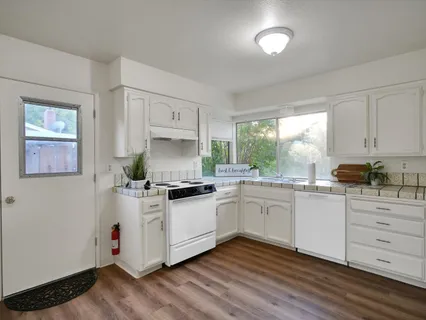 a kitchen with granite countertop white cabinets and white appliances