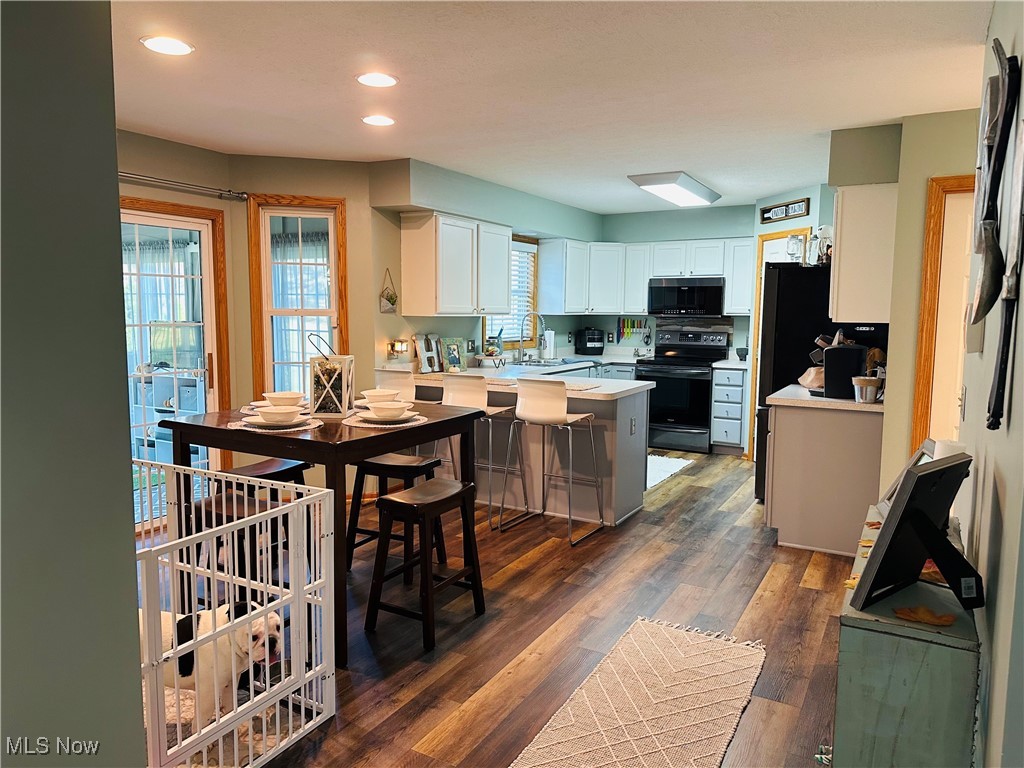 2435 Queensbury Road Alliance, OH 44601 - Photo 6 of 36 Kitchen featuring light countertops, black appliances, recessed lighting, a kitchen breakfast bar, and dark wood-type flooring