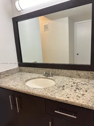 a bathroom with a granite countertop sink and a mirror