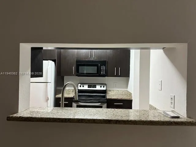 a kitchen with kitchen island granite countertop a refrigerator and a stove