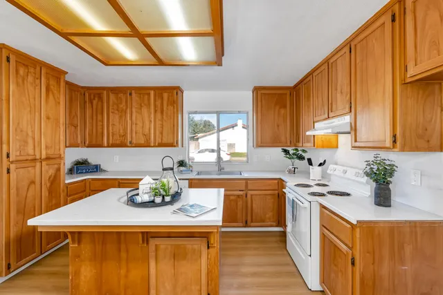 a kitchen with a stove a sink dishwasher and a refrigerator with wooden floor