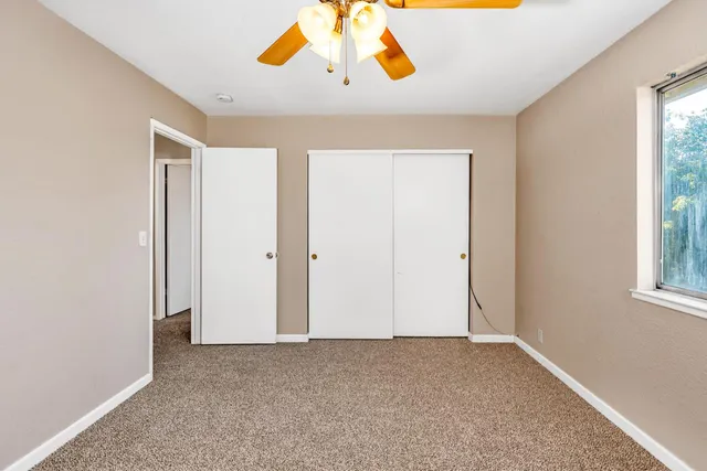 an empty room with a window and a fan