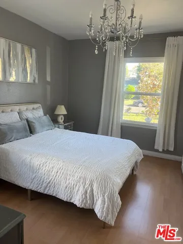 a bedroom with a bed chandelier and a window