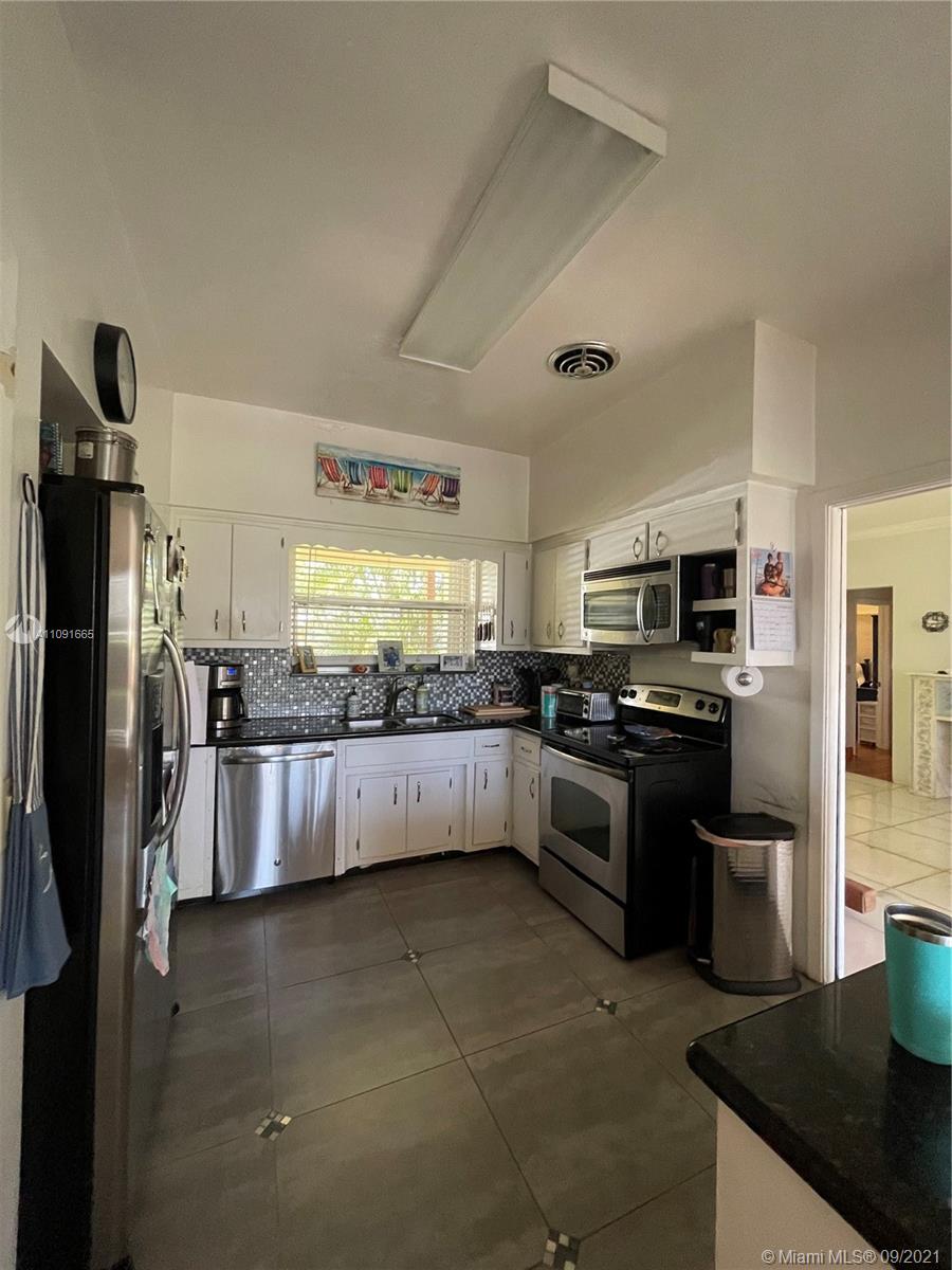 a large kitchen with stainless steel appliances kitchen island granite countertop a refrigerator and a stove top oven