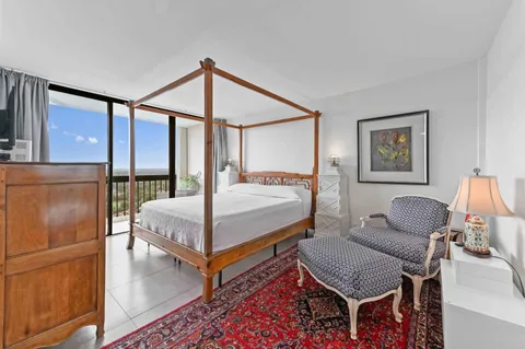 a bedroom with a bed a couch and a dresser with wooden floor